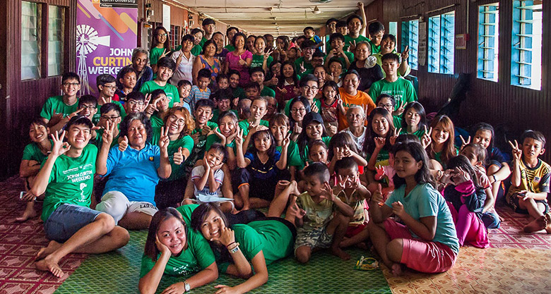 Volunteers pose for group photo with village folk at Rumah Nora.