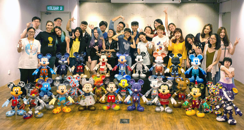Students, lecturers and staff members of The One Academy with the 25 units of two-foot Mickey figurines designed and decorated by them.
